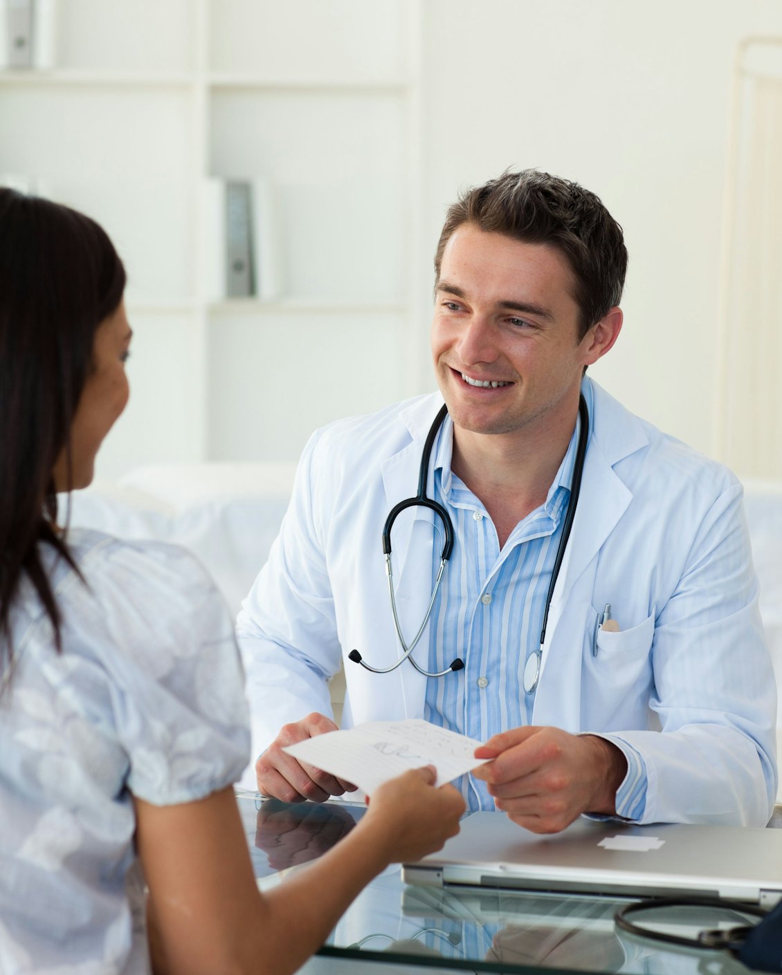 Arzt händigt seiner Patientin ein Rezept aus Arzt händigt seiner Patientin ein Rezept aus