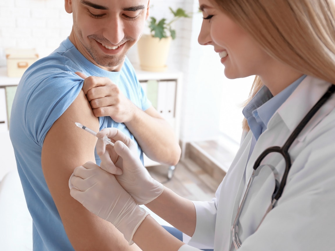 Ärztin impft einen jungen Mann Ärztin impft einen jungen Mann