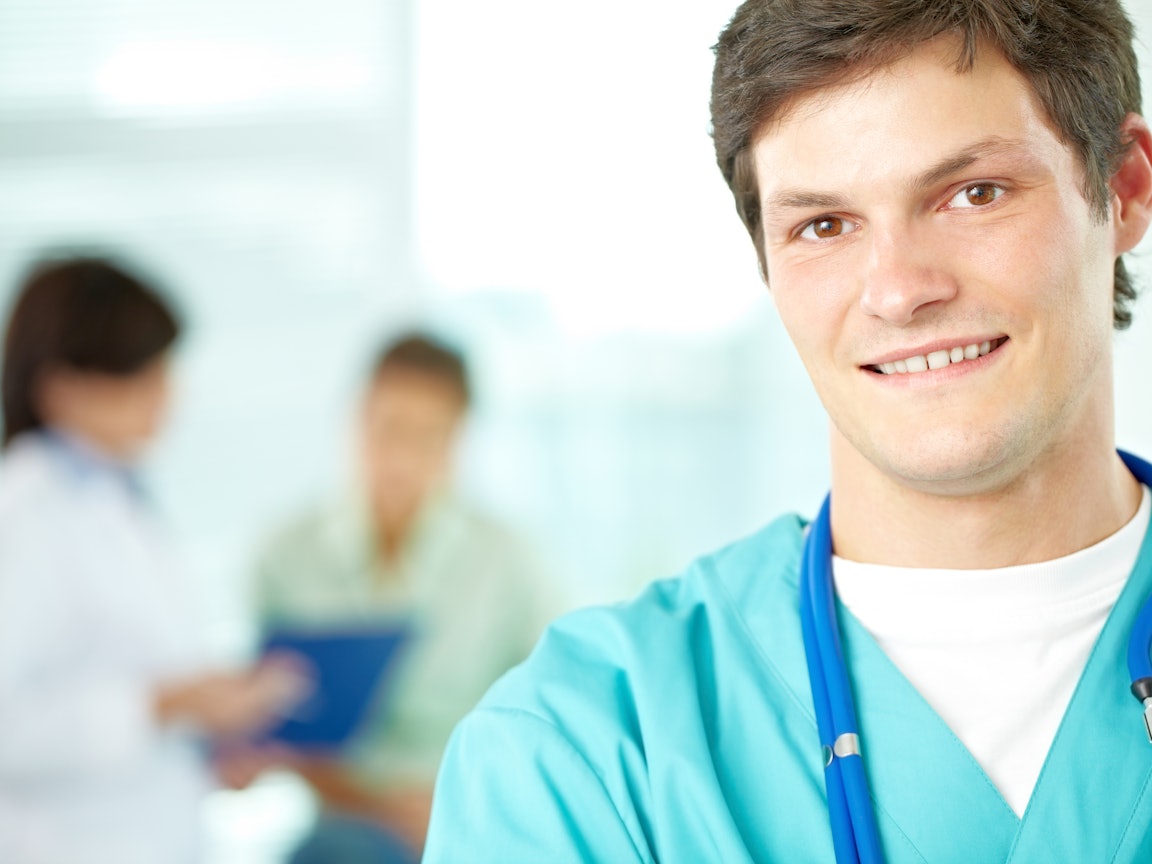 Junger Arzt mit Stetoskop lacht in die Kamera Junger Arzt mit Stetoskop lacht in die Kamera