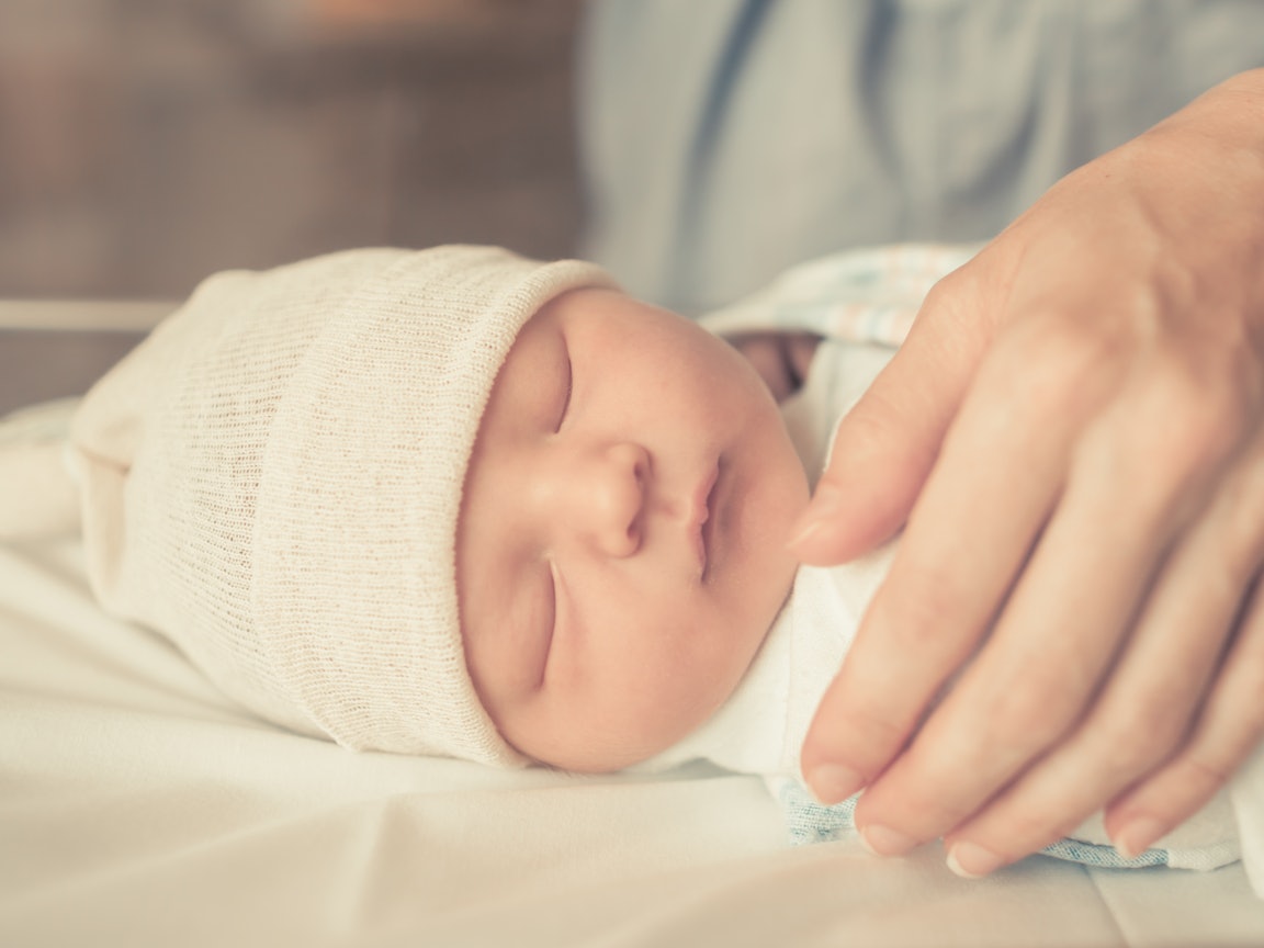 Neugeborenes wird von einer Hand geschützt
