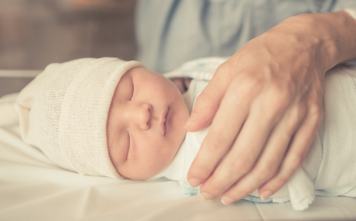 Neugeborenes wird von einer Hand geschützt