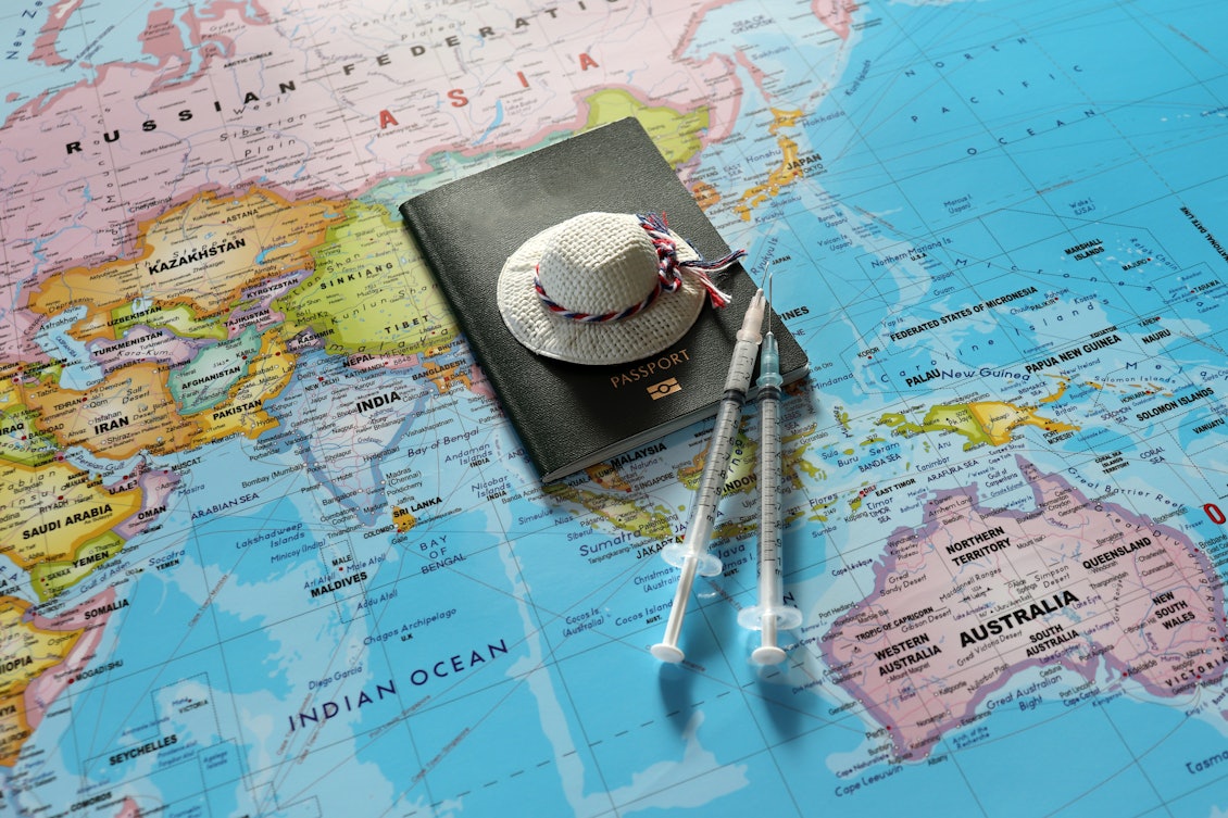 Passport mit Hut und Spritze liegen auf einer Weltkarte