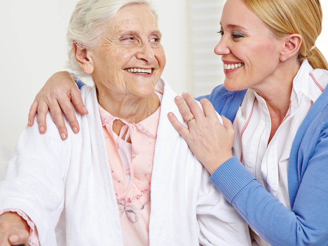 Junge Frau umarmt ältere Frau Junge Frau umarmt ältere Frau