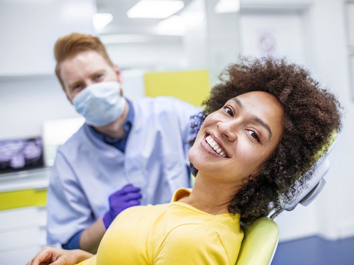 Frau sitzt auf dem Zahnarztstuhl für den Checkup. Sie lächelt. Frau sitzt auf dem Zahnarztstuhl für den Checkup. Sie lächelt.