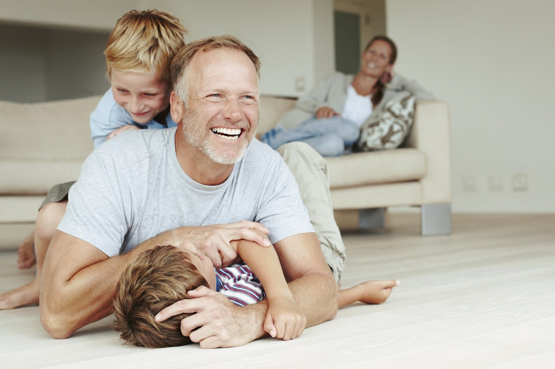 Vater spielt mit den Kinder auf dem Boden