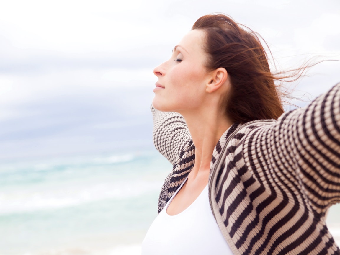 Frau steht mit geschlossenen Augen am Strand und genießt die Stimmung Frau steht mit geschlossenen Augen am Strand und genießt die Stimmung