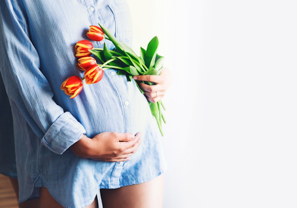 Frau mit Babybauch hält Tulpen in der Hand Frau mit Babybauch hält Tulpen in der Hand