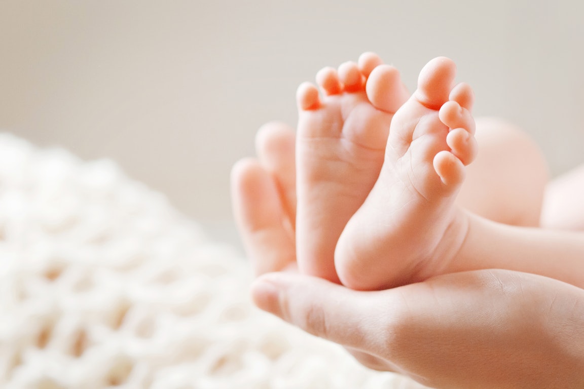 Hand umfasst die Füße eines Babies