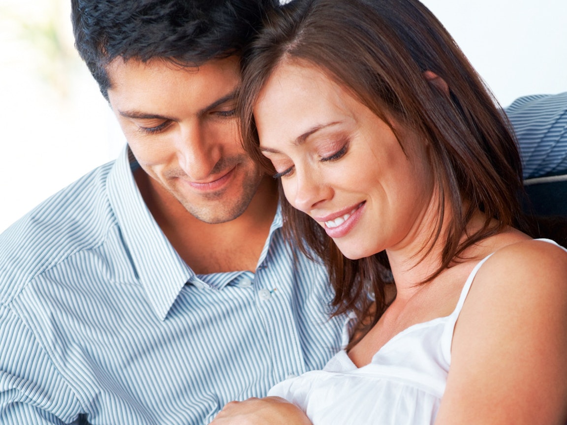 Junger Mann berührt den Babybauch seiner Partnerin Junger Mann berührt den Babybauch seiner Partnerin