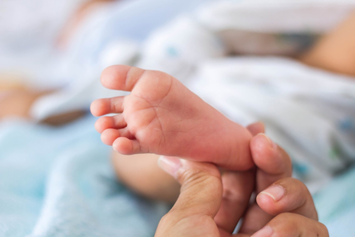 Fuß eines Neugeborenen wird gestreichelt