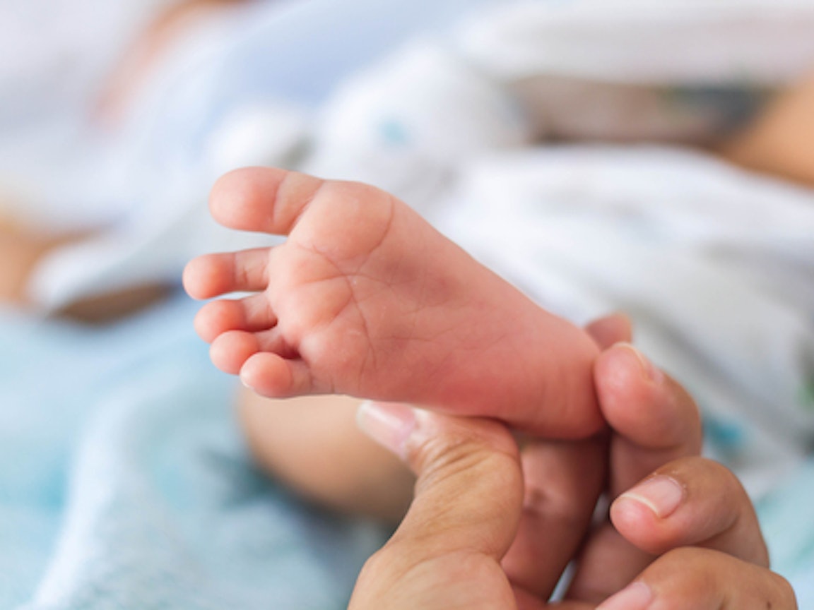 Fuß eines Neugeborenen wird gestreichelt Fuß eines Neugeborenen wird gestreichelt