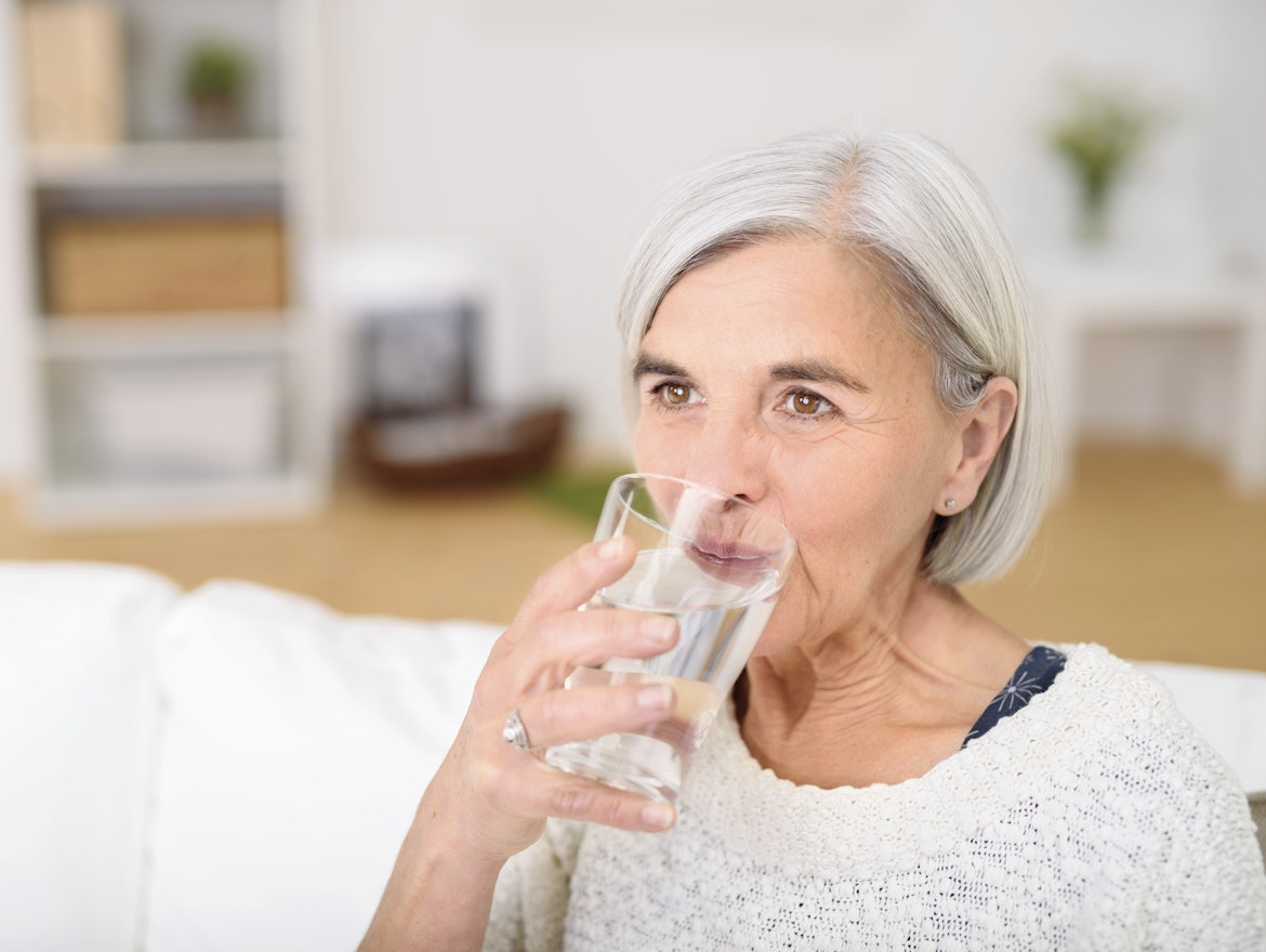 Mittelalte Frau trinkt ein Glas Wasser