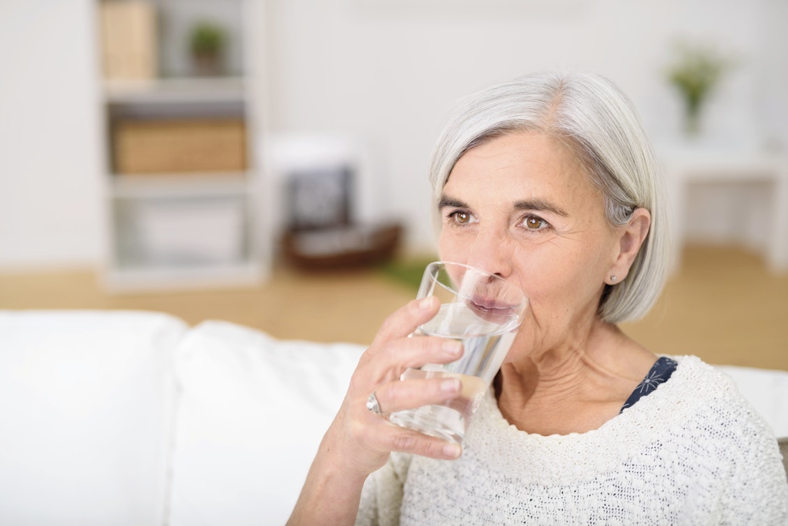 Mittelalte Frau trinkt ein Glas Wasser Mittelalte Frau trinkt ein Glas Wasser