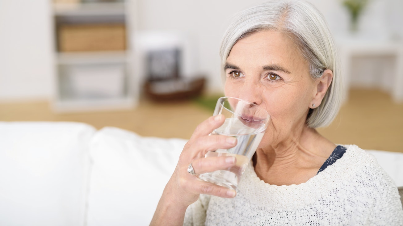 Mittelalte Frau trinkt ein Glas Wasser Mittelalte Frau trinkt ein Glas Wasser