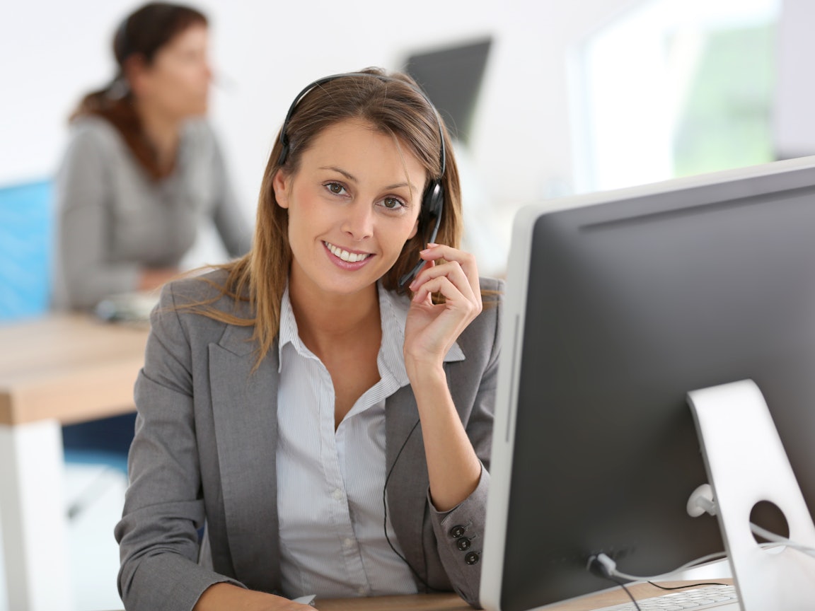 Junge Businessfrau mit Headset am PC Junge Businessfrau mit Headset am PC