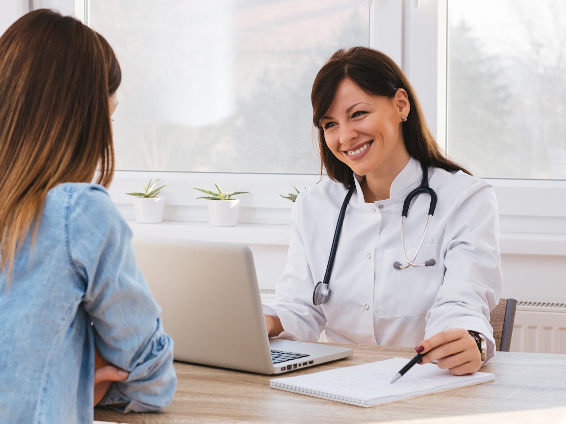 Junge Ärztin spricht gut gelaunt mit einer jungen Patientin Junge Ärztin spricht gut gelaunt mit einer jungen Patientin