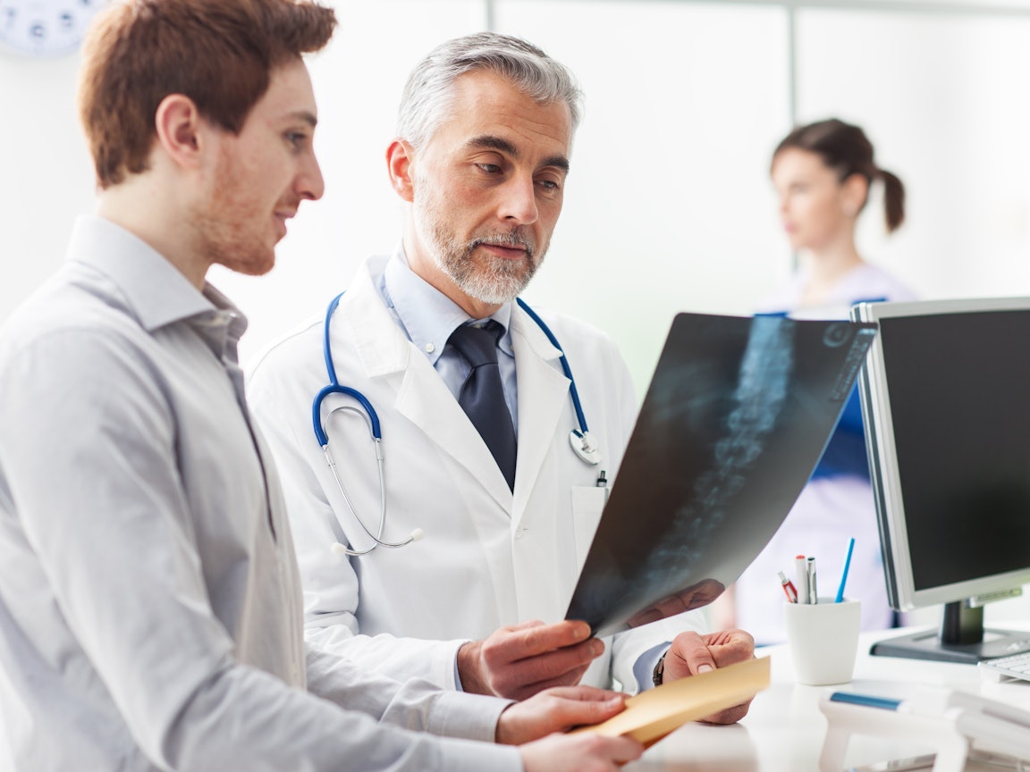Arzt bespricht Röntgenbild mit männlichem Patienten