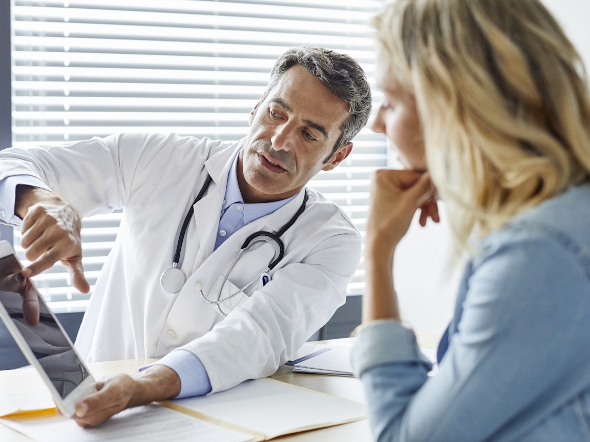 Arzt bespricht Röntgenbild mit einer Patientin Mittelalter Arzt bespricht Röntgenbild mit einer Patientin