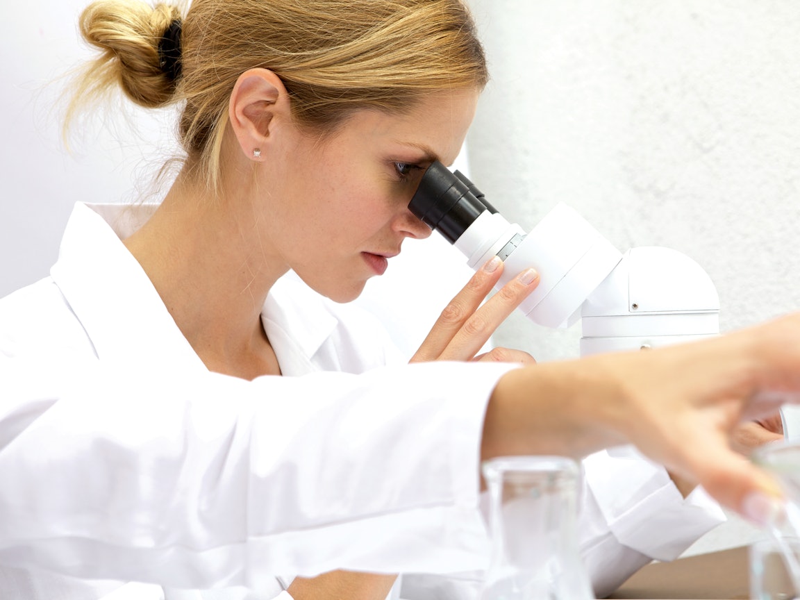 Ärztin untersucht etwas im Mikroskop Ärztin untersucht etwas im Mikroskop