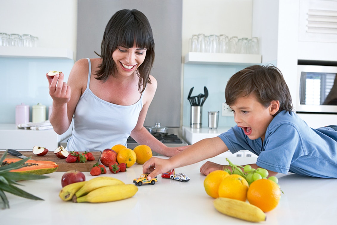 Mutter und Sohn essen Obst und spielen in der Küche