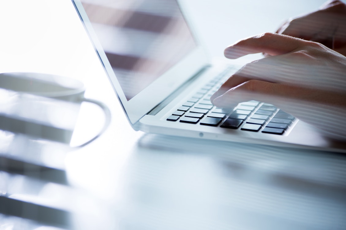 Männderhände tippen auf einem Laptop Aufgeklappter Laptop, an dem Männerhände eintippen