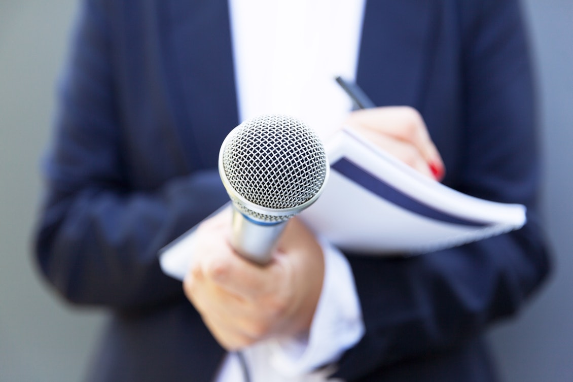 Prresseanfrage Reporter Reporterin hält Mikrofon und Block mit Stift in der Hand
