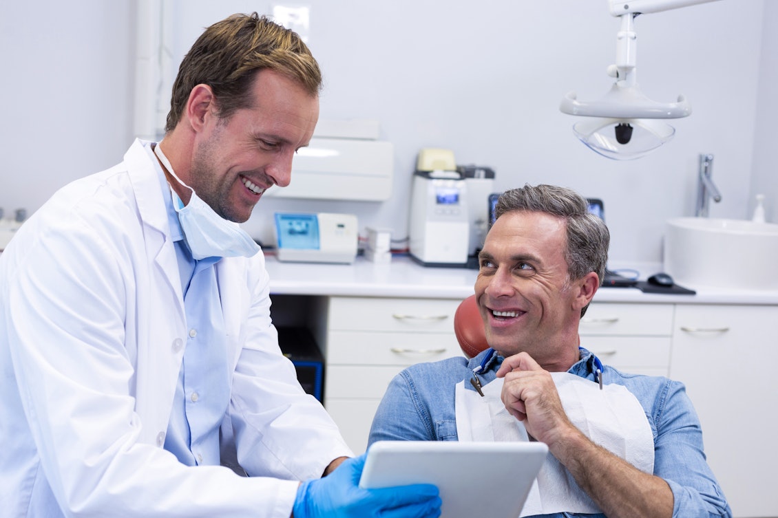 Zahnarzt berät einen Patienten mit Hilfe eines Tablets
