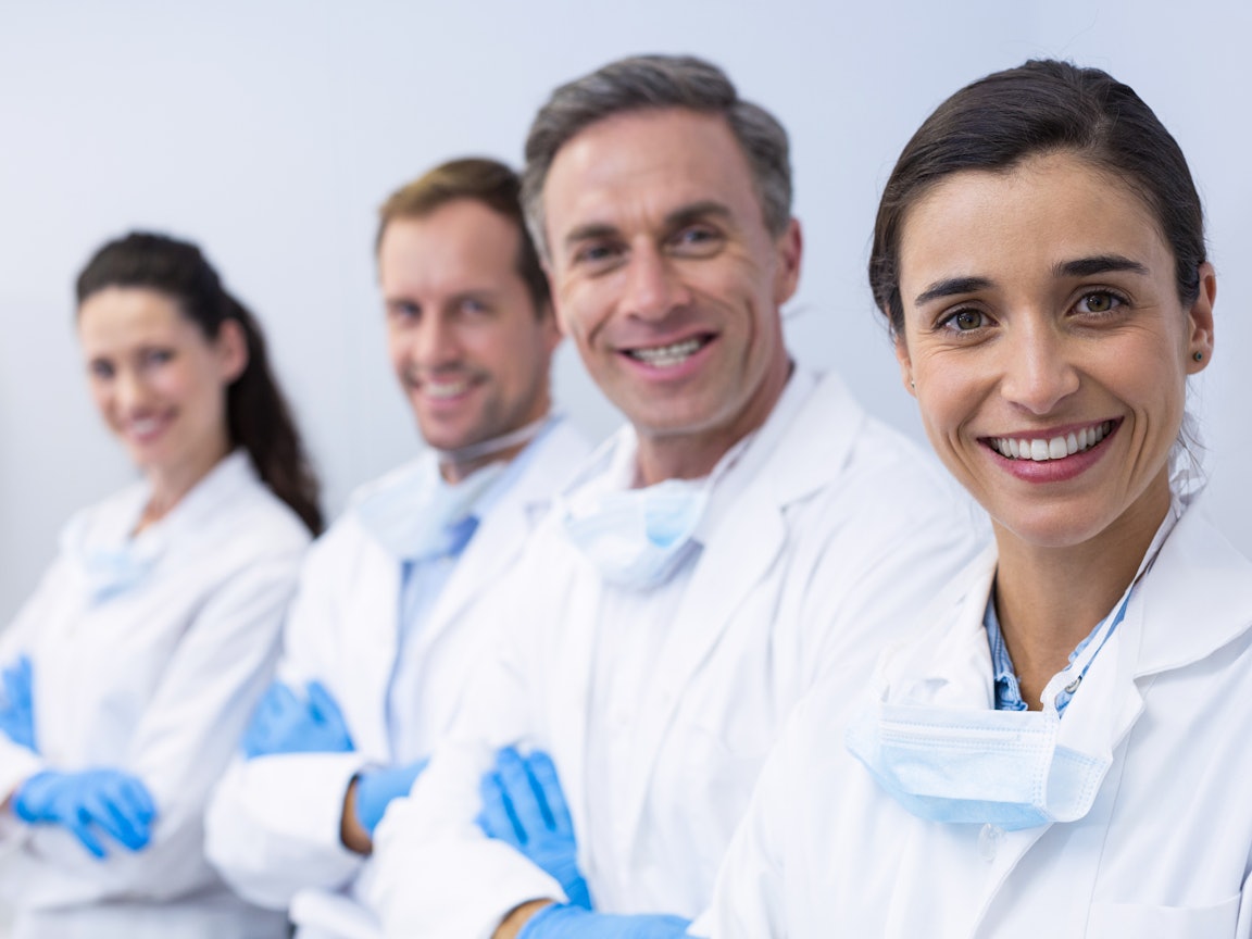 Lächelnde Zahnärzte Vier lächelnde Zahnärzte stehen in einer Reihe