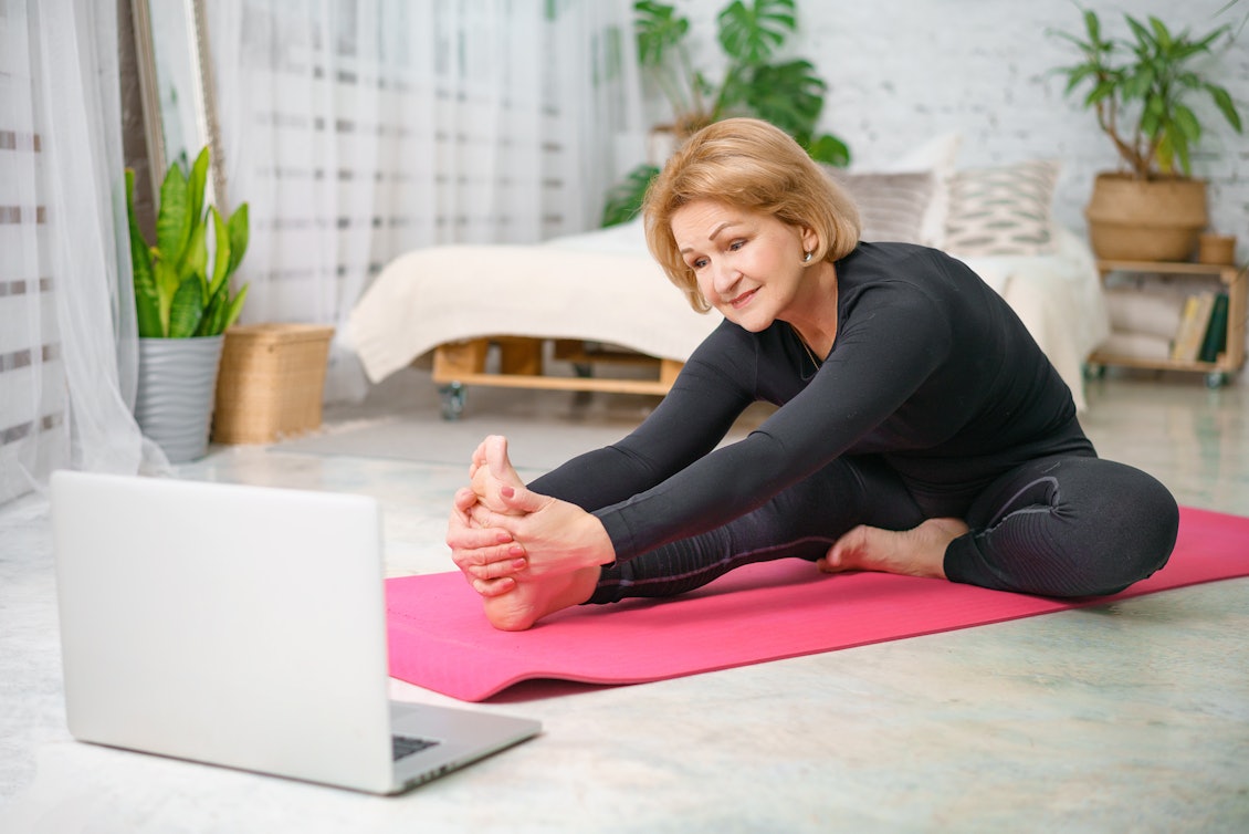 Seniorin dehnt sich auf Yogamatte