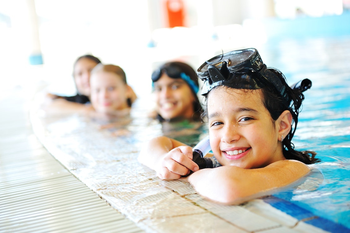 Vier Kinder am Rand eines Schwimmbeckens