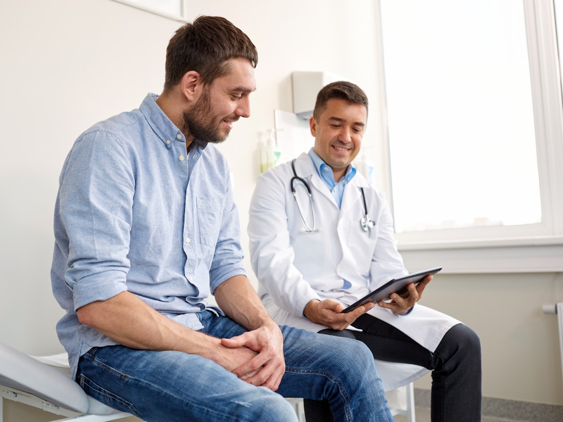 Vorsorgeuntersuchung beim Arzt Ein Mann und ein Arzt sitzen auf einer Liege und besprechen sich