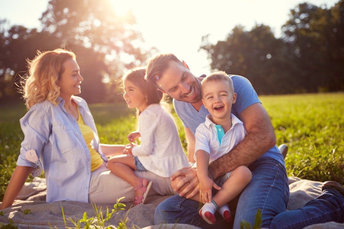 Eine Familie sitzt auf eine Decke im Park