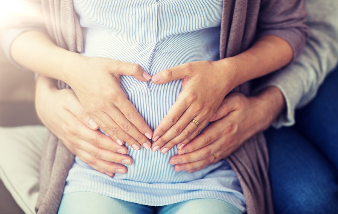 Mann und Frau haben die Hände auf den Bauch der schwangeren Frau gelegt