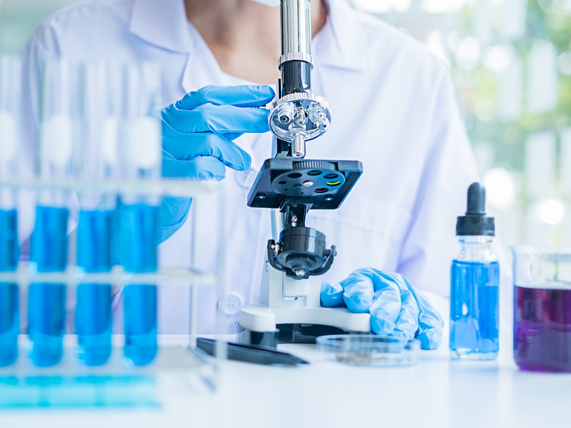 Untersuchung von Proben im Labor Eine Frau mit Handschuhen untersucht Proben am Mikroskop