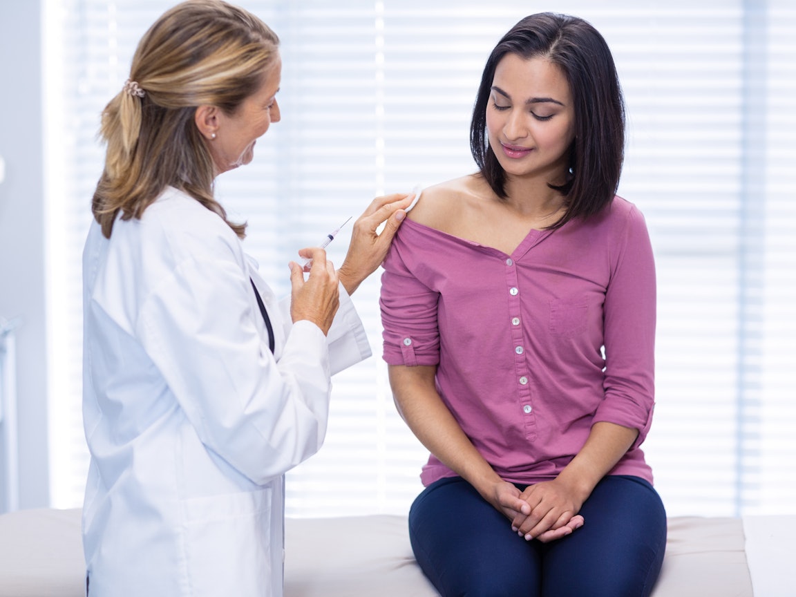 Ärztin gibt einer Frau eine Spritze in den Oberarm Ärztin gibt einer Frau eine Spritze in den Oberarm