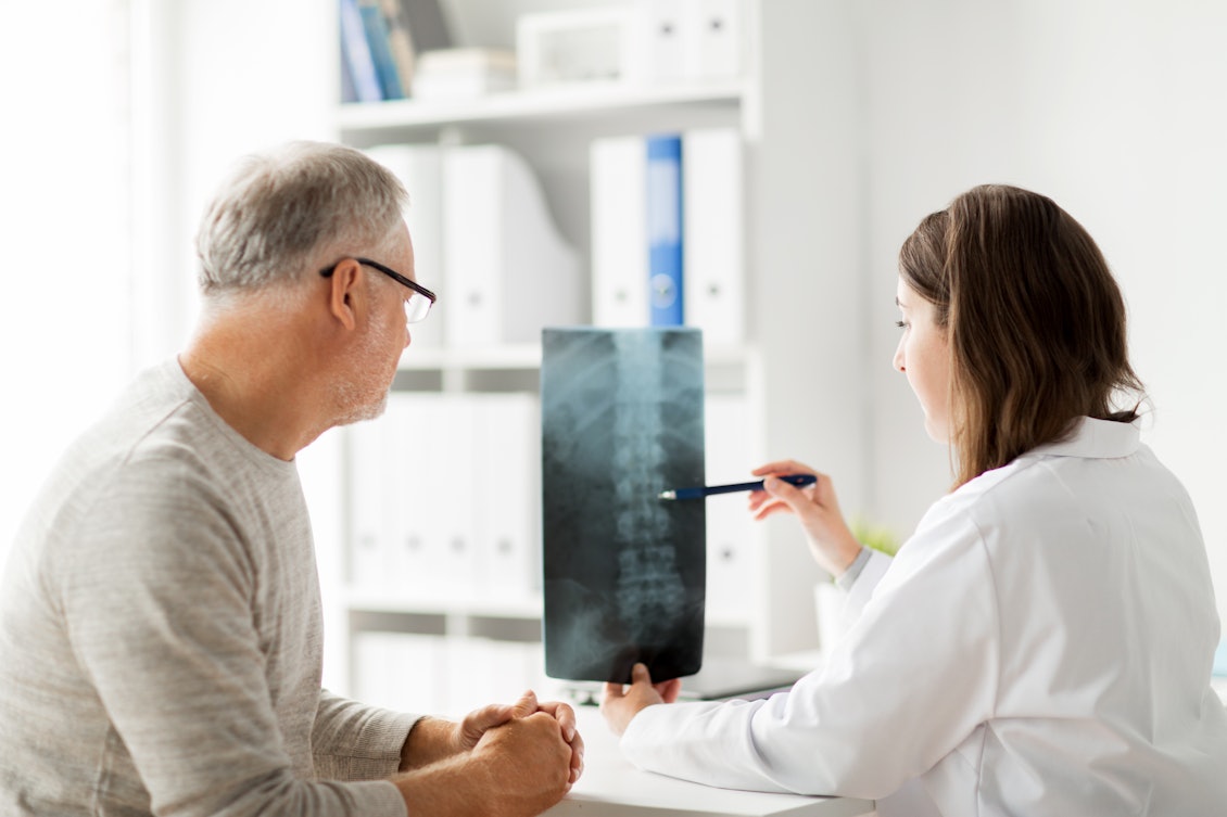 Ein älterer Mann bespricht ein Röntgenbild mit seiner Orthopädin
