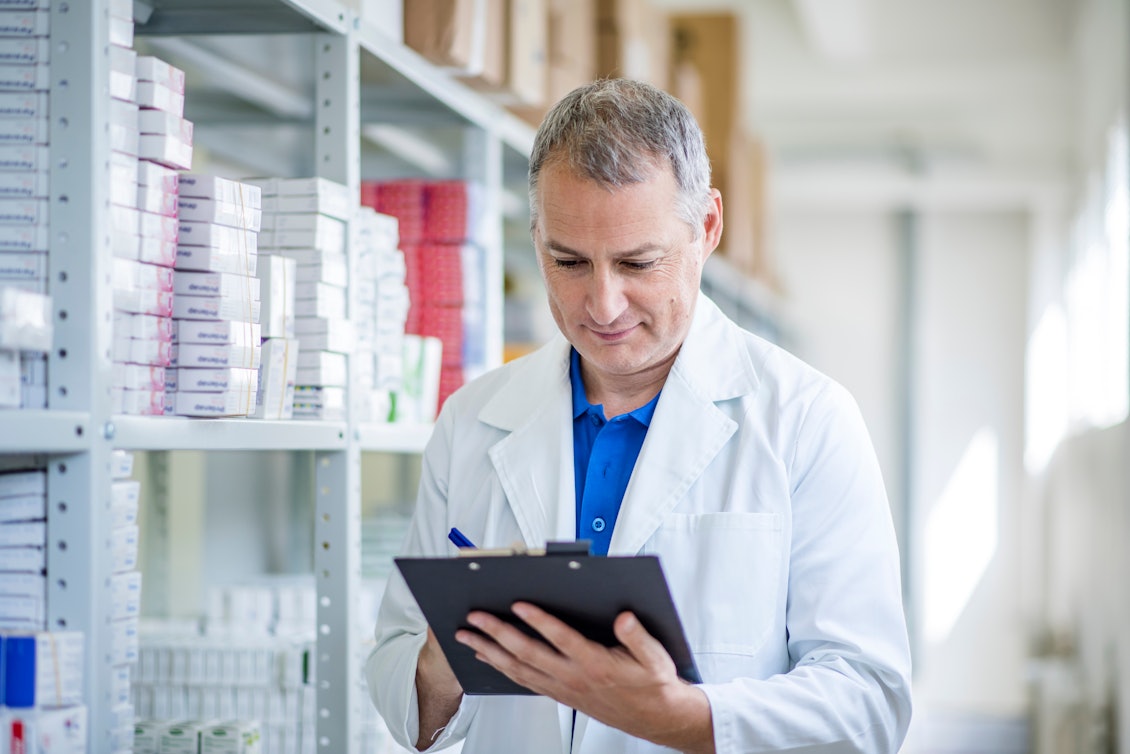 Die Pflegehilfsmittel müssen von anerkannten Leistungserbringern kommen Ein Apotheker steht in einem Lager, das mit Medikamenten gefüllt ist