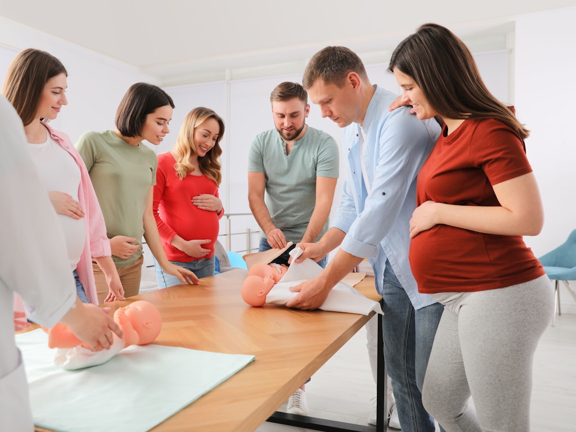 Werdende Mütter und Väter im Geburtsvorbereitungskurs Gruppe von Männer und Frauen im Geburtsvorbereitungskurs