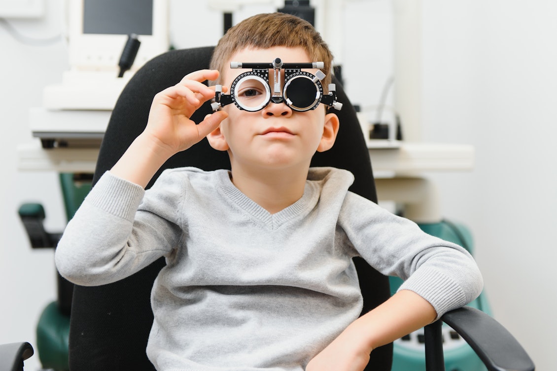 Die Behandlung bei Amblyopie beginnt beim Augenarzt Ein Junge sitzt beim Augenarzt und hat ein Testgerät auf der Nase