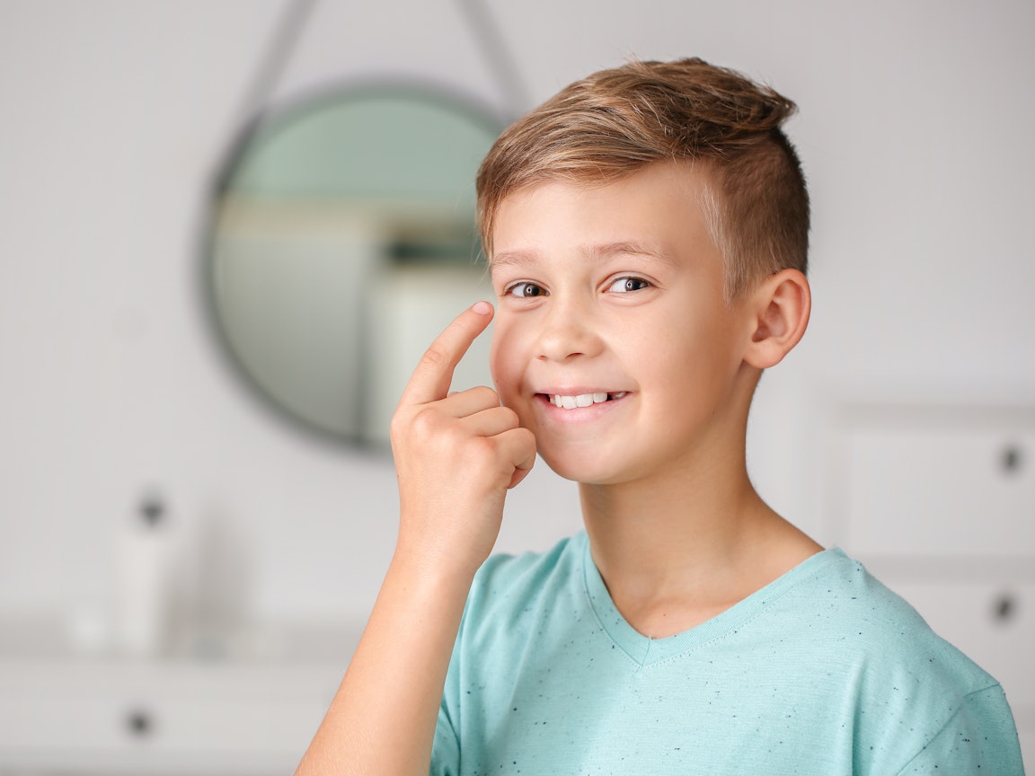 Die Online-Sehtherapie trainiert beide Augen gleichmäßig Ein Junge zeigt mit dem rechten Zeigefinger auf sein rechtes Auge