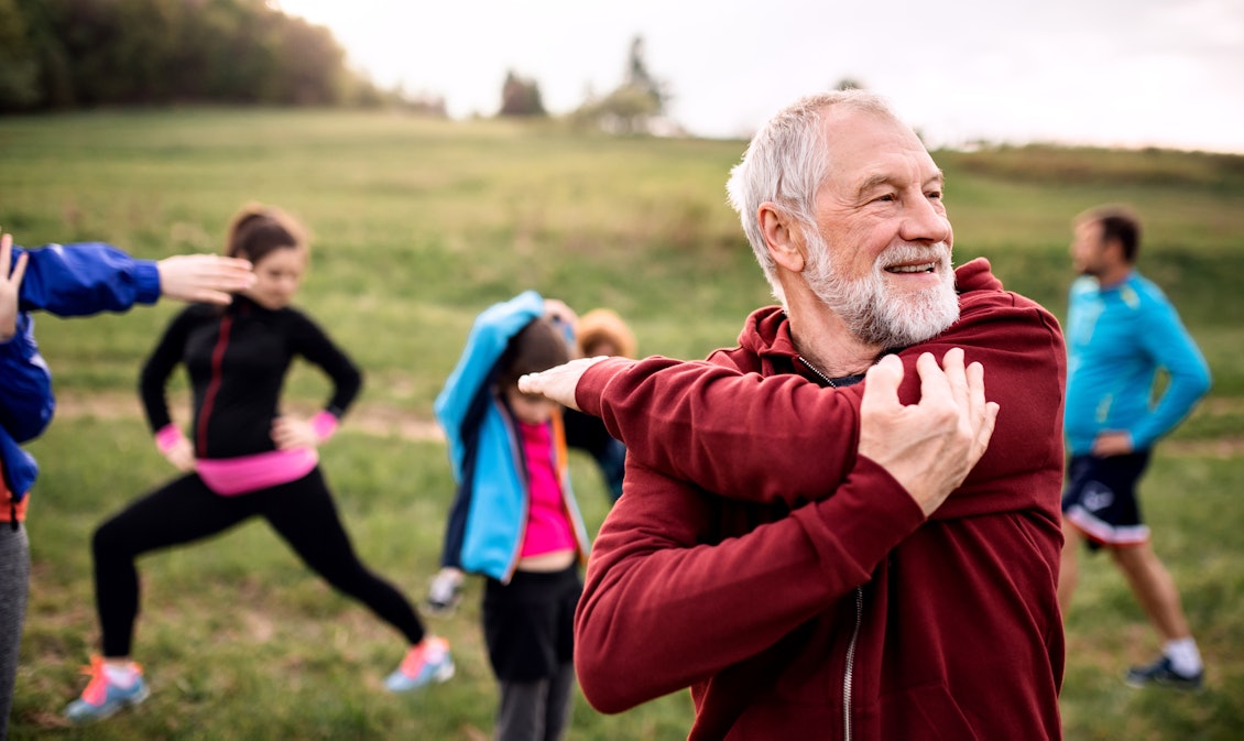 Präventionskurse eignen sich für jung und alt Ein älterer Mann mit weißen Haaren wärmt sich für eine Sporteinheit auf
