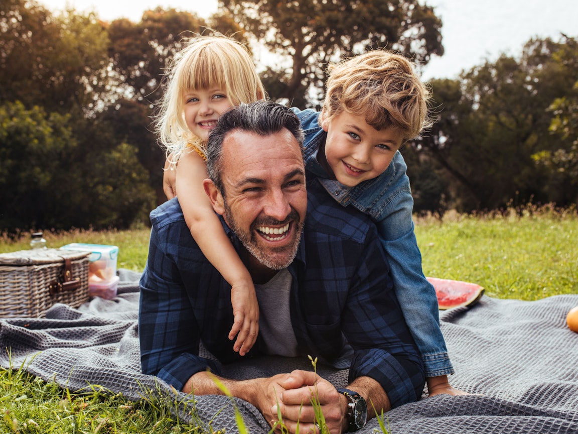 Vater mit zwei Kindern beim Picknick Vater mit Kindern im Grünen