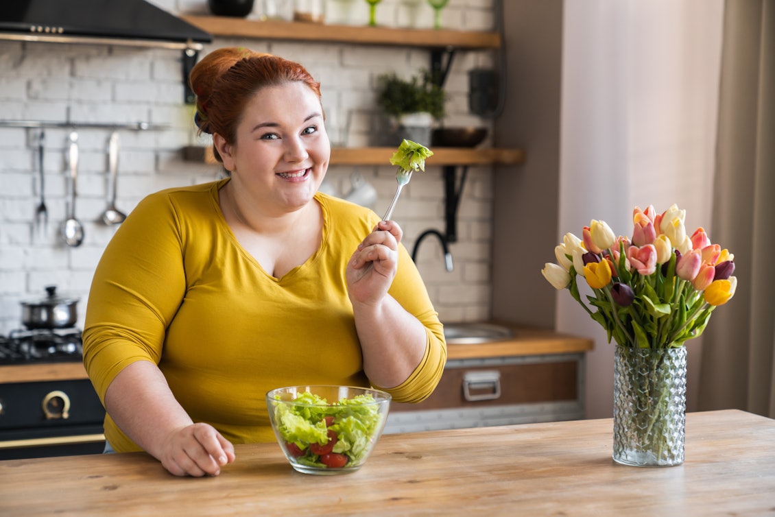 Eine übergewichtige Frau isst Salat
