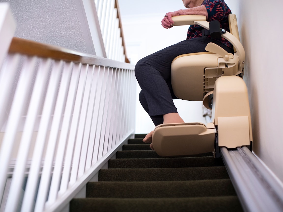 Ein Treppenlift erleichtert das Leben enorm Eine ältere Frau fährt im Treppenlift nach oben