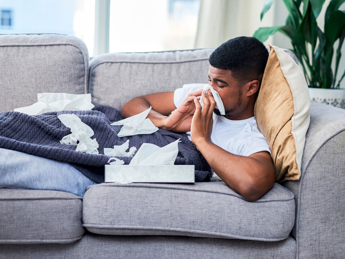 Ein junger Mann liegt krank auf dem Sofa Ein junger Mann liegt krank auf dem Sofa