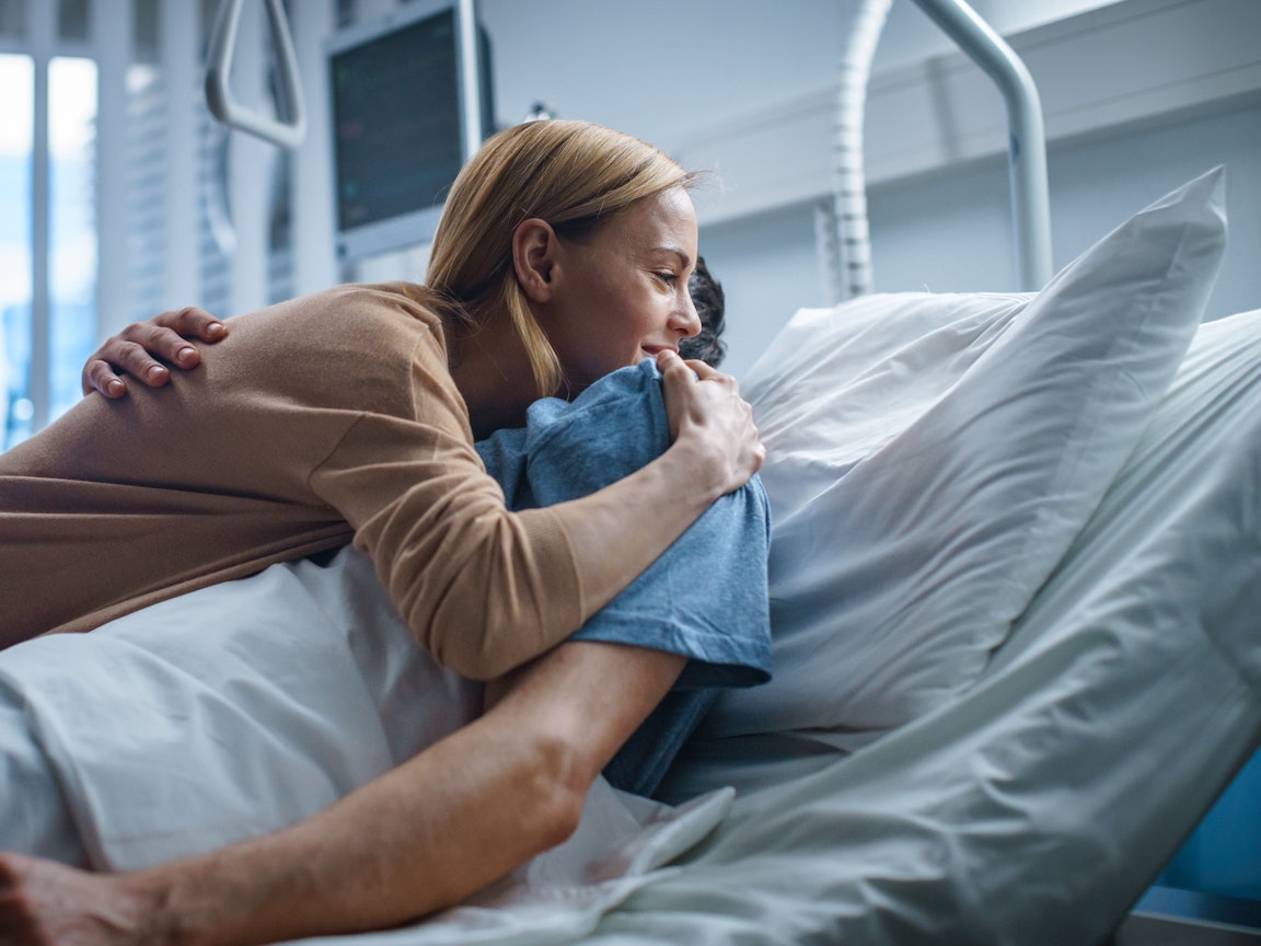 Frau umarmt einen Patienten im Bett Frau umarmt einen Patienten im Krankenhaus