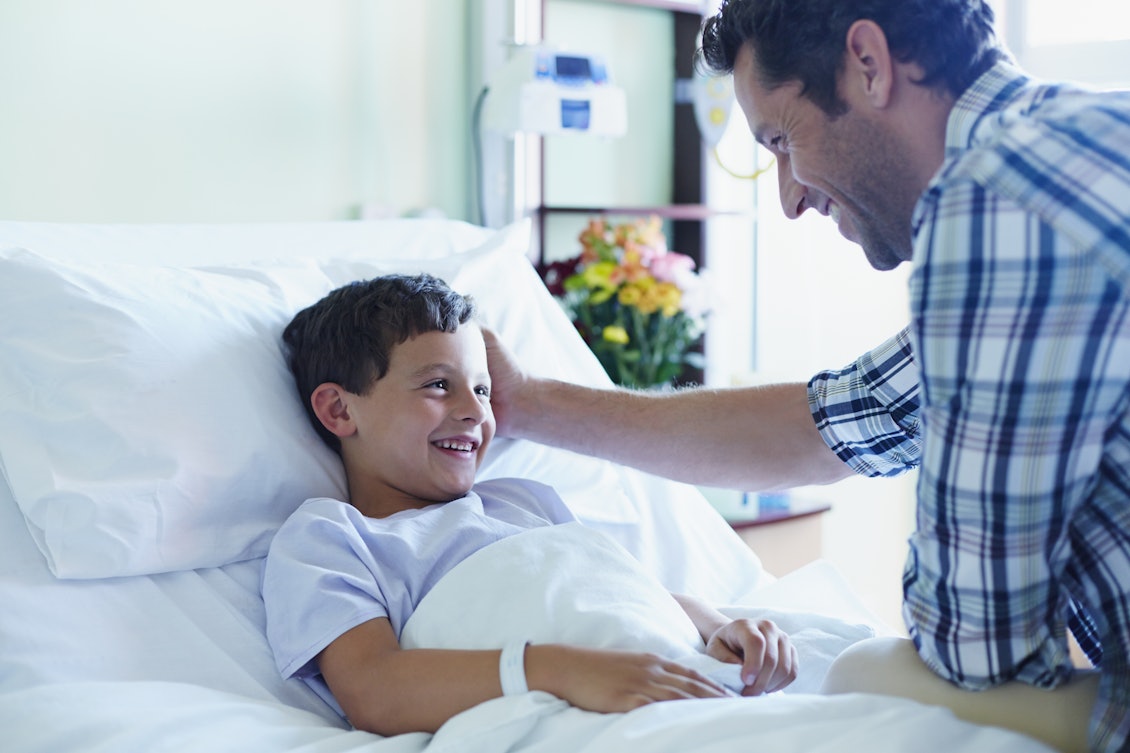 Vater und Sohn gemeinam im Krankenhaus Ein Vater besucht seinen Sohn im Krankenhaus und streichelt den Kopf seines Sohnes