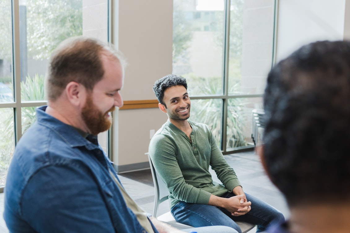 Zwei Männer sitzen nebeneinander und lächeln