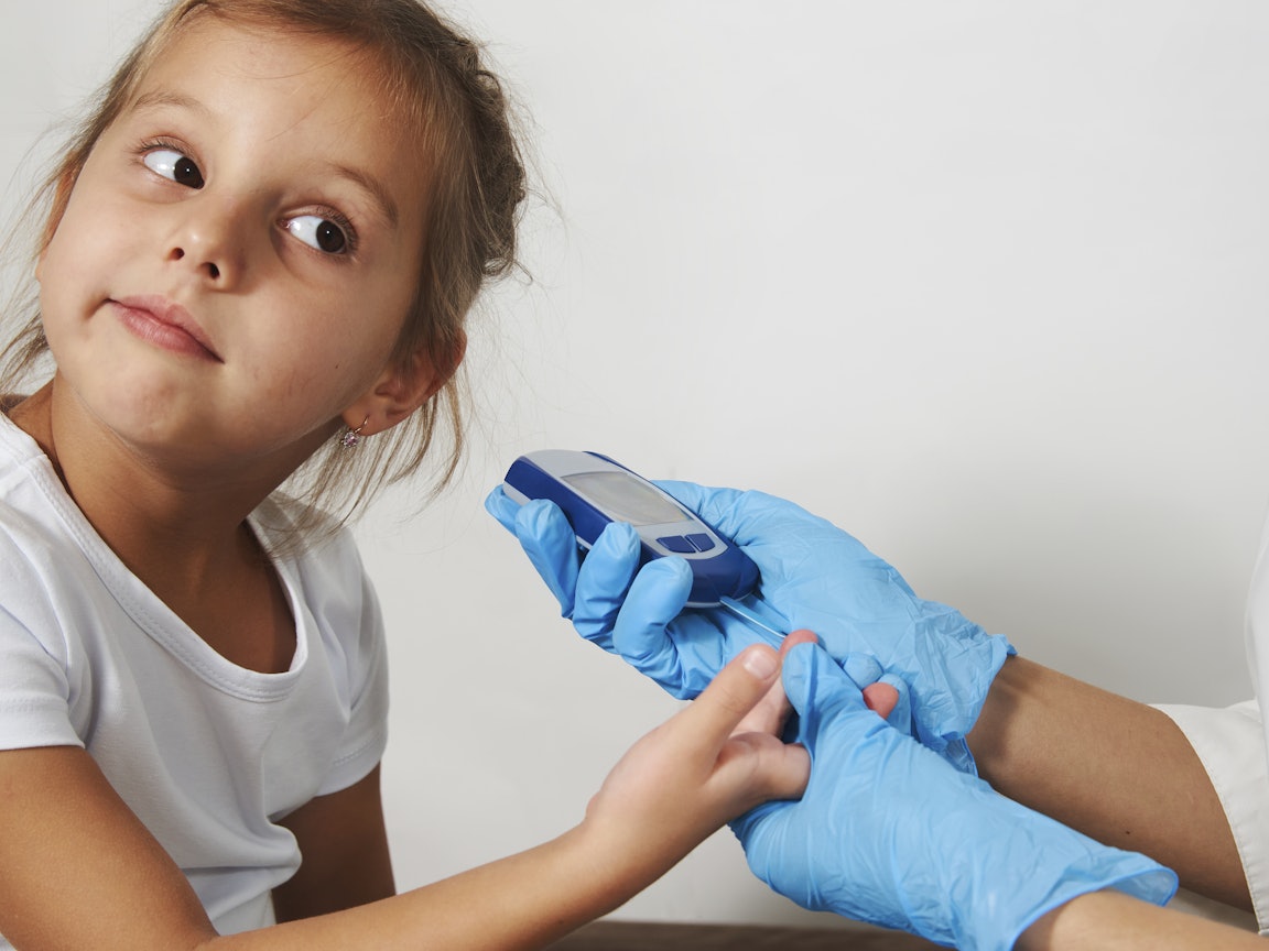 Junges Mädchen bei der Messung des Blutzuckerspiegels Der Blutzuckerspiegel eines jungen Mädchens wird gemessen