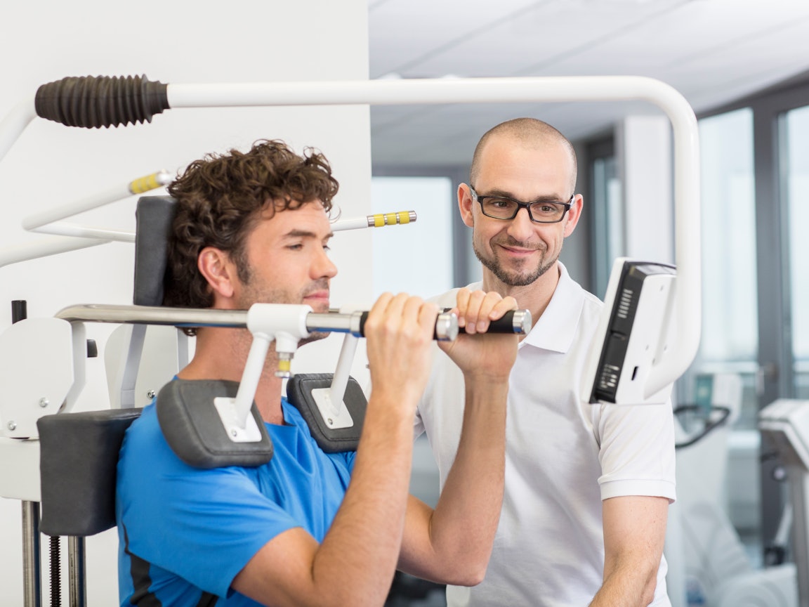 Trainer erklärt einem Patienten eine Übung Trainer erklärt einem Patienten eine Übung